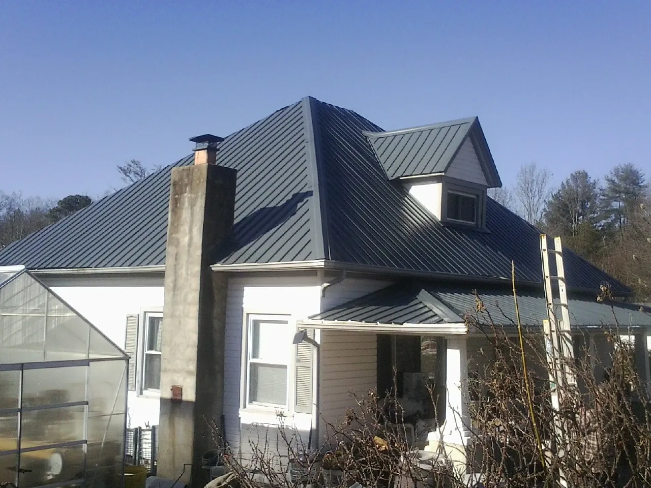 Dark blue standing seam metal roof on a white farmhouse with dormer — Slate & Tile Roof Repair by Roofing Brothers in South Thomaston