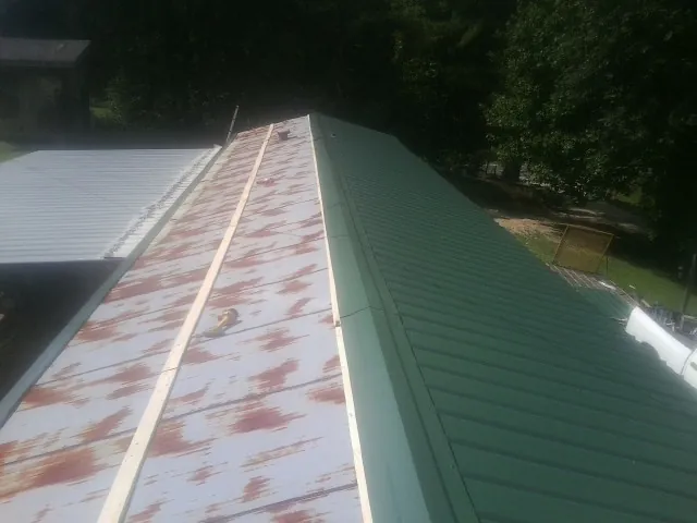 Old rusted panels beside newly installed green metal roofing — Wind Damage Roof Repair by Roofing Brothers in South Thomaston