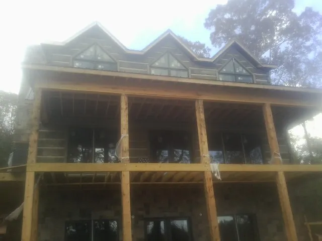 Dormers and porch framing on a large log home under construction — Roof Coating work by our crew in South Thomaston