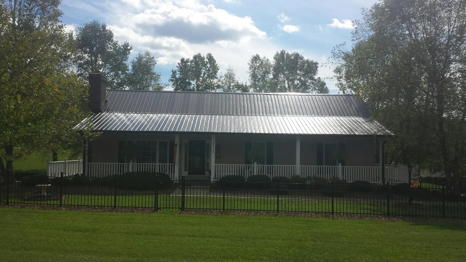 Gray metal roof on a brick ranch with a full width front porch — Gutter Guard Installation work by our crew in South Thomaston