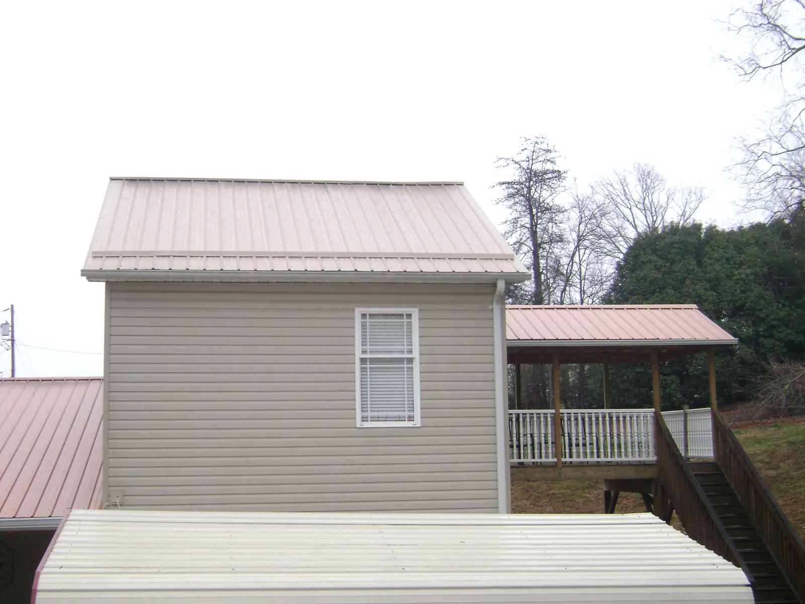 Tan metal roofs on a two story addition and attached porch, from a Roof Replacement job in South Thomaston
