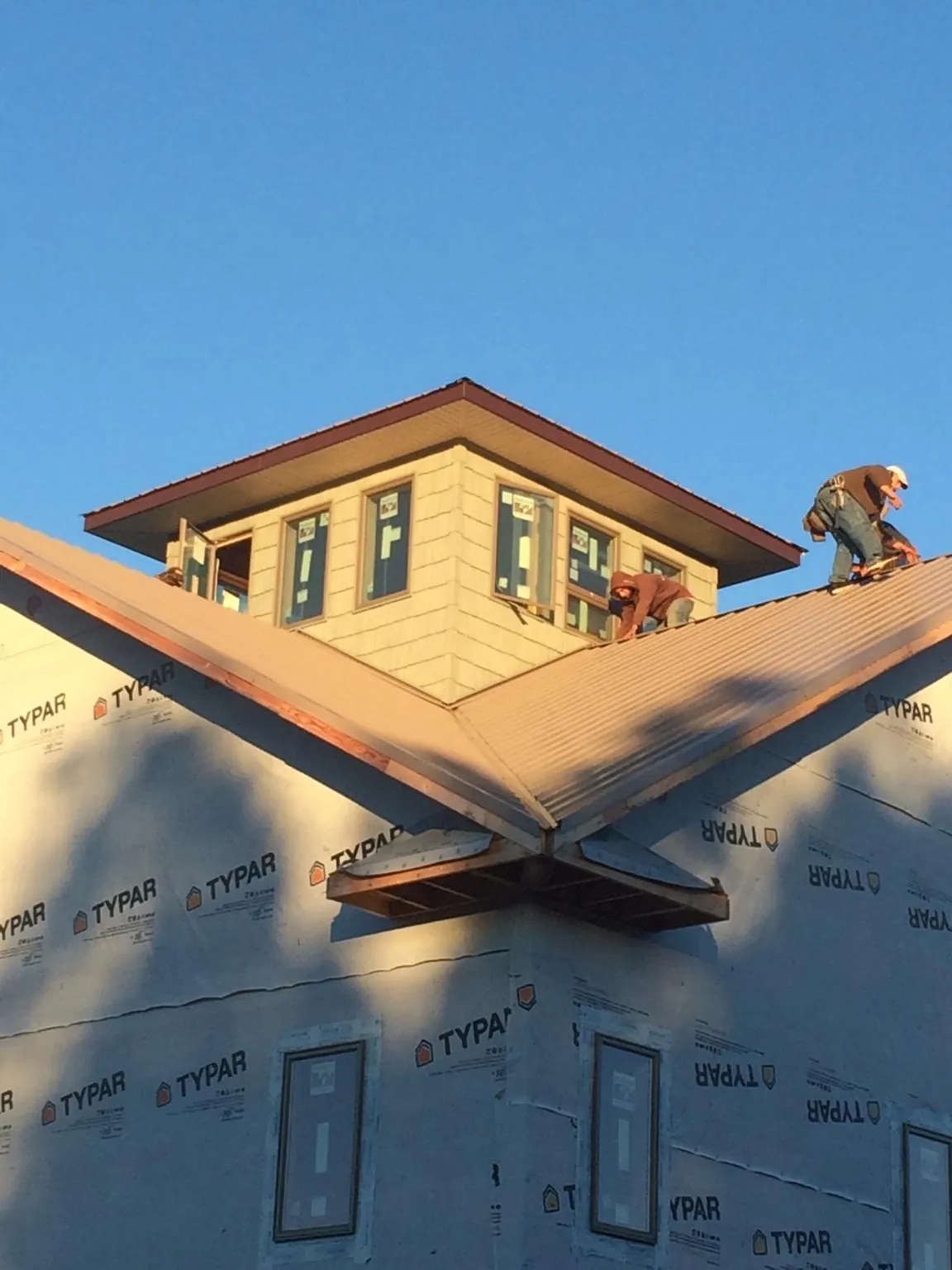 Roofers working around a rooftop cupola on a new metal roof at sunset — Roof Waterproofing in South Thomaston by Roofing Brothers